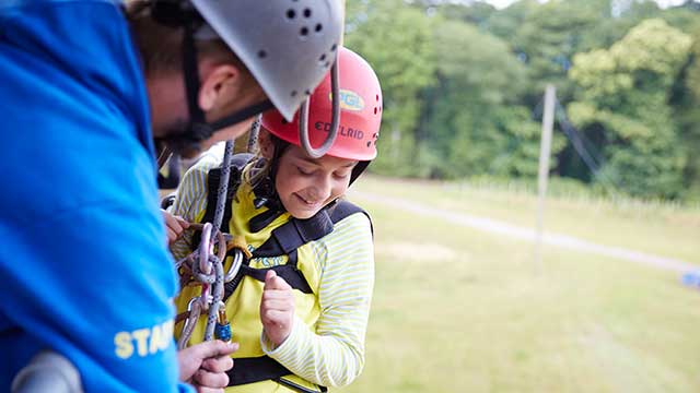 An instructor helping a Brownie abseil down a tower at PGL